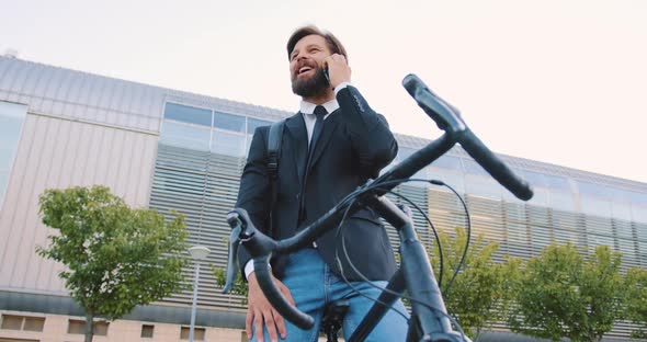 Male Office Manager with Beard Sitting on Own Bike Near Modern Big Building