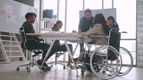 A disabled company employee is able to work happily with colleagues in the office.