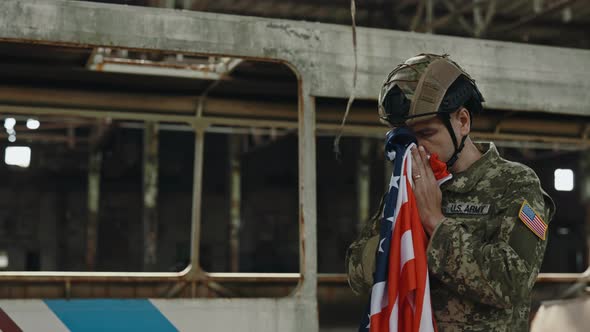 Military Man Holding American Flag in Destroyed Building