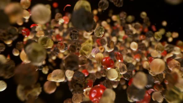 Super Slow Motion Detail Shot of Color Pepper Falling Down on Black Background at 1000Fps