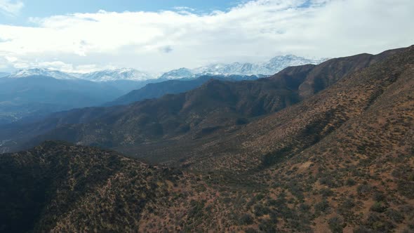 Aerial view dolly in of San Carlos de Apoquindo Park with the snowcapped El Plomo Hill in the backgr