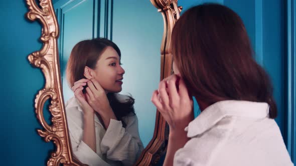 SLOW MOTION Beautiful Asian woman looking in a mirror looks at the beauty of her face with a smile