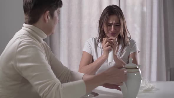 Portrait of Young Beautiful Caucasian Woman Crying As Sitting at the Table with Mom. Senior Brunette