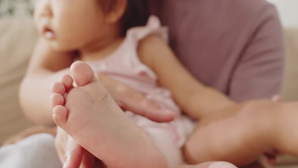 Loving Asian Mom Sitting with Sweet Baby Girl at Home