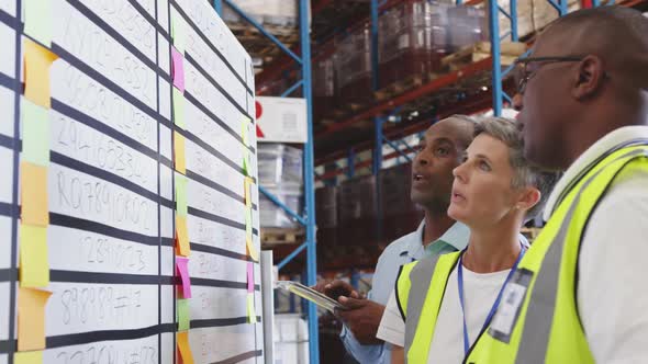 Warehouse staff in discussion at an information board 4k