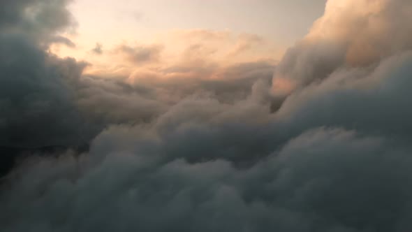 Aerial View Flying Through Cumulus Thunderclouds at Sunset. Gold Colored Sunset Cloudiness in High