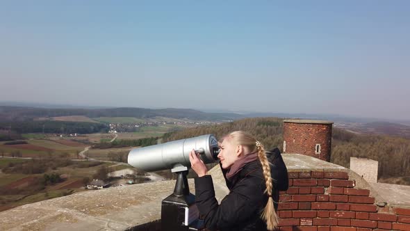 Attractive Female Traveller Using Tower Optical Viewer for Looking Around Valley Near the Old Castle