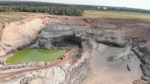 Huge open quarry with mounds of minerals. Machinery excavators digging clay quarry.
