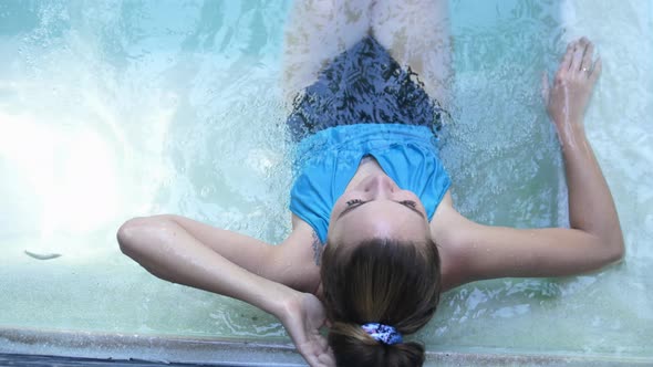 Top of View of Beautiful Young Woman Relaxes in a Hydromassage Jacuzzi in Swimming Pool