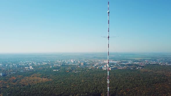 one telecommunication tower is located near the city in the background of the forest.