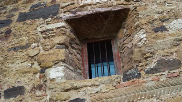 Barred window of an ancient church with an old stone wall 