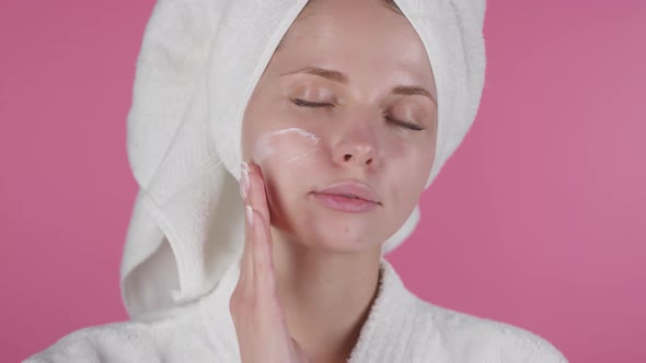 Beautiful Woman Applying Cream to Face after Shower