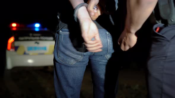 Police Officer Puts Handcuffs on Arrested Man at Night and Leads Him to a Police Car