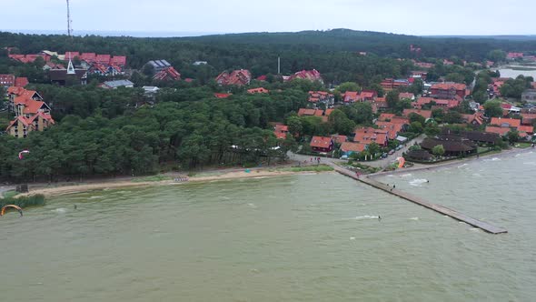 AERIAL: Rotating Shot of Bay Filled With Kite Surfers and Homes in the Background