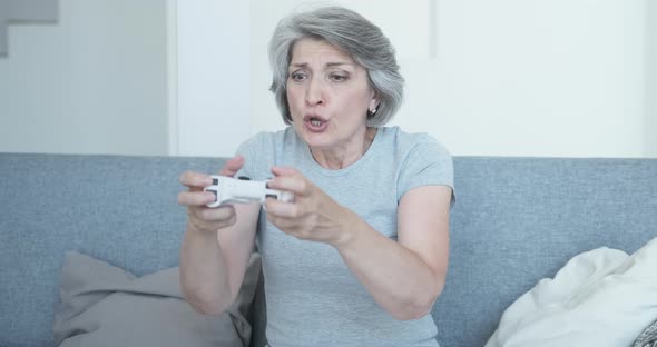 A Very Emotional Senior Citizen Plays Video Games at Home on the Couch