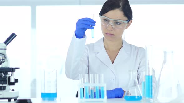 Doctor Looking at Blue Solution in Test Tube in Laboratory