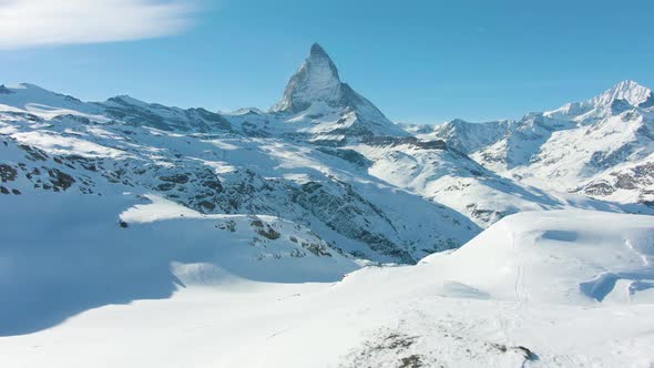 Blue Matterhorn Mountain and Hiker in Winter Day. Swiss Alps, Switzerland. Low Level Flight Over Man