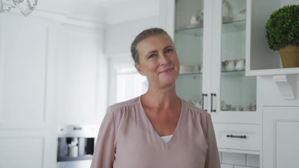 Portrait of smiling senior caucasian woman looking at camera in kitchen