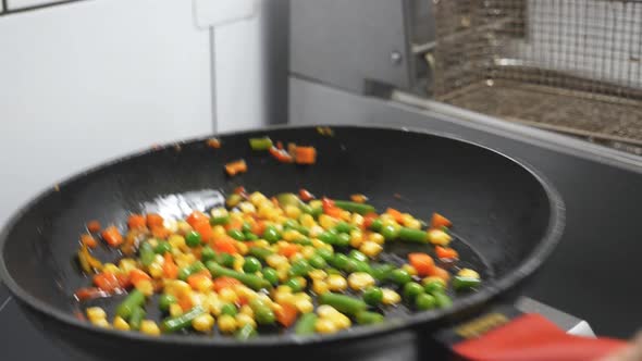 Male Arm of Cook Holding Skillet and Tossing Up Mixed Vegetables at Kitchen Restaurant