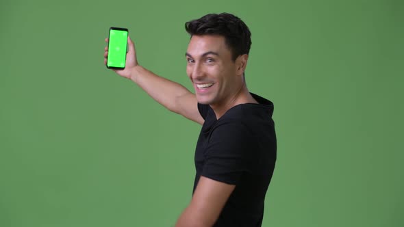 Young Handsome Hispanic Man Against Green Background