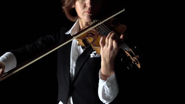 Girl Bows a Violin in a Dark Room. Black Background. Close Up