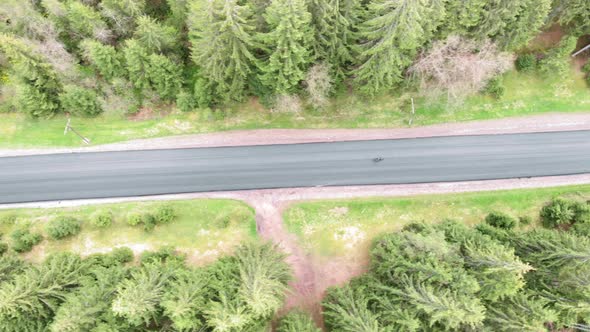 Cycling from drone. Cyclist cycling on country road in mountains top aerial view