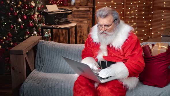 Elderly Man in Santa Claus Costume Reading Email Wish List Use Laptop
