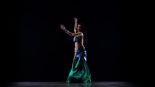 Girl Performing a Belly Dance in Dark Studio. Black Background. Slow Motion