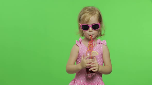 Child in Pink Swimsuit Drinks Juice Cocktail with Drinking Straw. Chroma Key