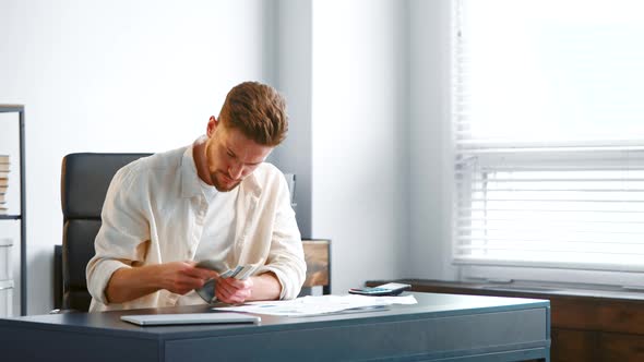 Concentrated company manager with beard counts money banknotes