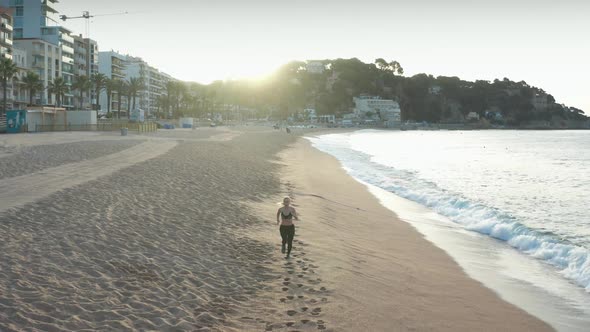 Aerial Shot of Female Running Fast Along Beach