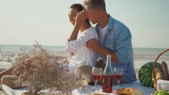 Affectionate Young Family Couple Happy Husband and Wife Sit on Cozy Picnic Blanket with Wine Fruits