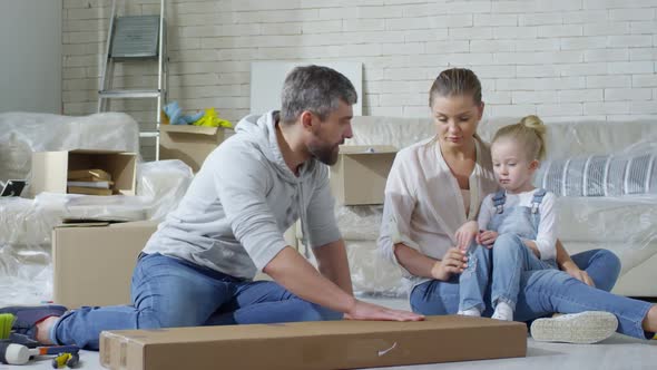 Girl Helping Father Opening Package