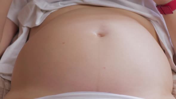 Pregnant womans belly with baby moving and kicking inside