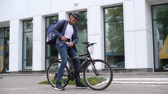 Young Caucasian Courier Male Delivering Food with Transportation Thermo Backpack Looking for