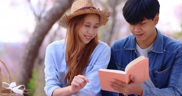 Slow motion romantic moment of young Asian couple reading book together.