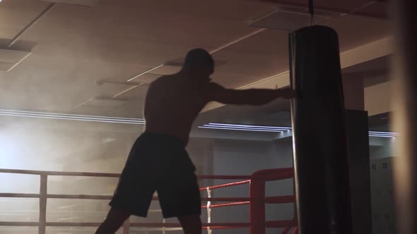 Kickboxing Athletic Man Fighter Trains His Punches Beats a Punching Bag Trains Kicking Skills in the