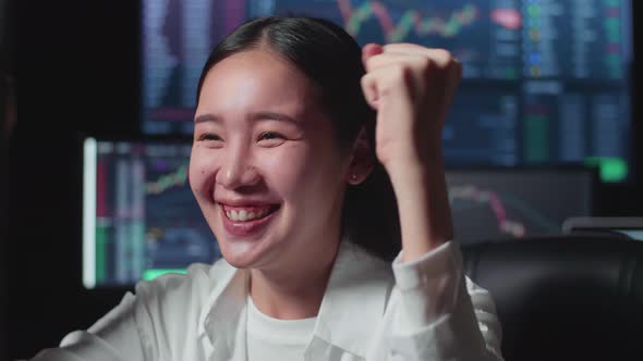 Asian Female Stock Market Broker Working On Computer And Celebrating With Analysing Graphs