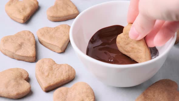 Dip heart cookies in chocolate. Valentine's day food concept.