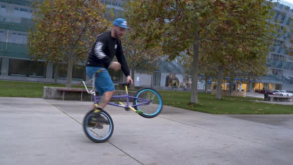 Guy riding a BMX bike in a skatepark,doing spinning and balance stunts.