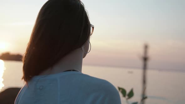 Girl looks out at the water during sunset