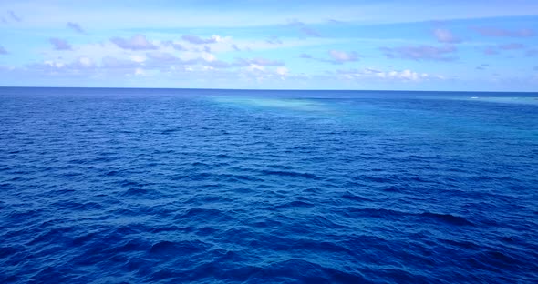 Natural flying abstract shot of a white paradise beach and blue water background in vibrant 4K