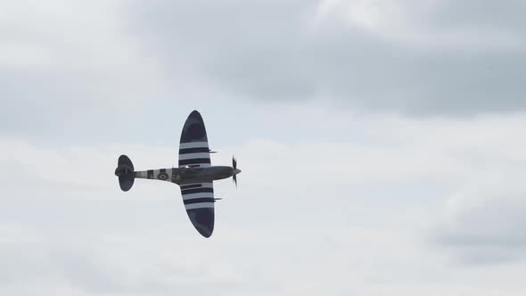 Slow motion of a D-Day Spitfire flying past the crowd during an air show.