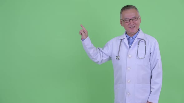 Happy Mature Japanese Man Doctor Talking and Touching Something