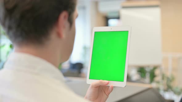 Young Man Looking at Tablet with Green Chroma Screen