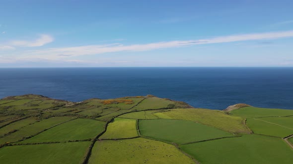 Blue sea and green English countryside color contrast. Aerial forward