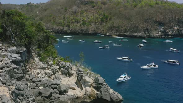 aerial revealing a tropical white sand beach at crystal bay with boats anchored in nusa penida bali