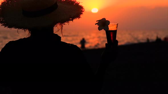 Woman on the Beach at Sunset Drinking a Cocktail