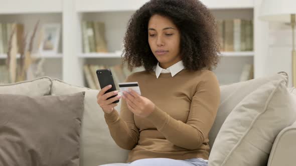 Online Shopping Success on Smartphone By Young African Woman on Sofa