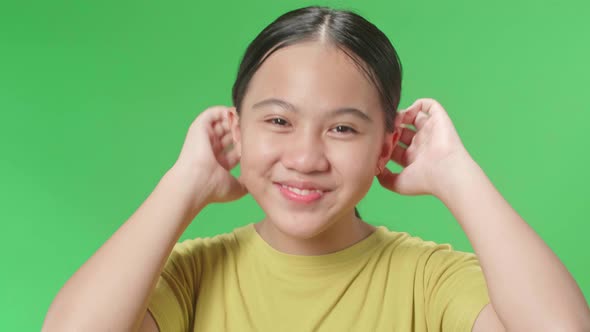 Asian Kid Girl Touching Her Hair While Looking At Camera Like A Mirror On Green Screen In Studio